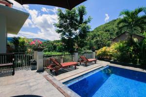 a swimming pool with two chairs and an umbrella at Dewi Villa in Padangbai