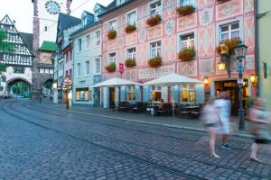un grupo de personas caminando por una calle con edificios en Zum Roten Bären, en Freiburg im Breisgau