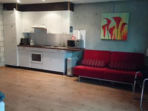 a living room with a red couch and a kitchen at Studios Faoug in Faoug