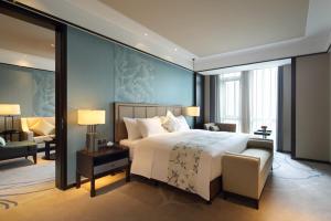 a bedroom with a large white bed and a chair at Wanda Realm Bozhou in Bozhou