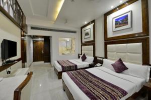 ein Hotelzimmer mit zwei Betten und einem Fernseher in der Unterkunft Hotel Emerald in Chandīgarh