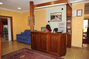 a woman sitting at a reception desk in a lobby at Hotel Valentini Inn in Foligno