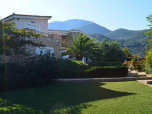 a house with a garden and mountains in the background at Luxury Villa Flora Kiparissia in Kyparissia