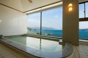 a swimming pool in a building with a view of the water at Bekkan Yosanoso in Miyazu
