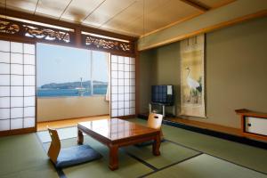 a living room with a table and a large window at Bekkan Yosanoso in Miyazu