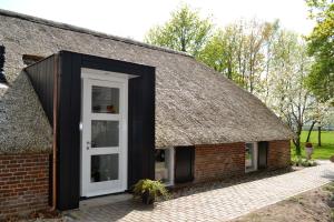 an extension to a thatch roofed house with a white door at Op de Kuyerlatten in Zwolle