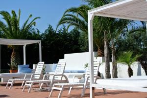 加拉托內的住宿－坎皮拉提尼農家公寓式酒店，庭院里摆放着一组白色的椅子和遮阳伞