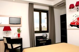 a bedroom with a bed and a desk and a window at Hotel Visagi in Pompei