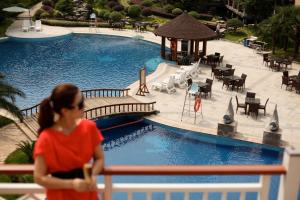 a woman standing on a fence near a swimming pool at Pullman Zhangjiajie Hotel - Instagrammable in Zhangjiajie
