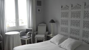 1 Schlafzimmer mit einem Bett, 2 Stühlen und einem Fenster in der Unterkunft Chambres d'hôtes Christa in Saint-Pair-sur-Mer