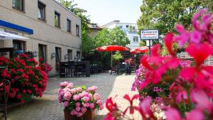 Ein Haufen rosa Blumen auf einer Straße mit Sonnenschirmen in der Unterkunft Hotel Fürstenhof in Braunschweig