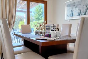 een eettafel met witte stoelen en een raam bij Villa Lara - 11 in Kouklia