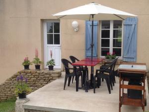 a patio with a table and chairs and an umbrella at La Cle des Champs in Provency