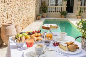 einen Tisch mit Frühstückszutaten und Getränken neben einem Pool in der Unterkunft Hotel Casa Peya - Adults Only in Palafrugell