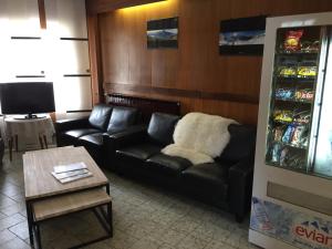 a living room with a black leather couch and a table at Hôtel Mont-Brison in Briançon