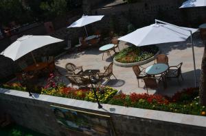 eine Terrasse mit Tischen, Stühlen, Sonnenschirmen und Blumen in der Unterkunft Tahir Aga Konagi Hotel in Trabzon