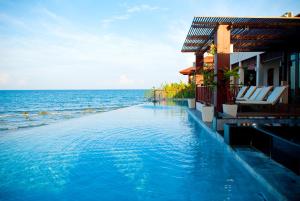 a swimming pool in front of a building next to the ocean at The Sarann - SHA Extra Plus in Chaweng Noi Beach