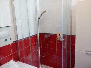 uma casa de banho com um chuveiro com azulejos vermelhos e brancos em Apartment Garson em Zagreb