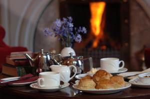 un tavolo con piatti di dolci e tazze e un camino di Arnolds Hotel a Dunfanaghy