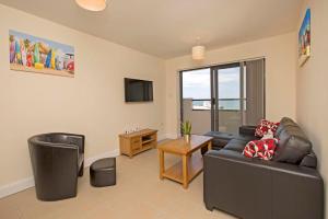 a living room with a leather couch and a tv at Westbeach Resort in Westward Ho