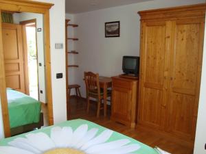 een slaapkamer met een bed en een televisie en een tafel bij Affittacamere La Falconetta in Champoluc