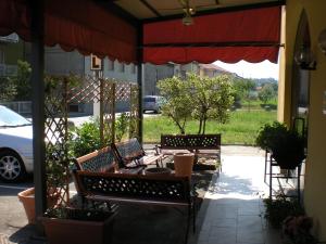 un patio con due panche e un ombrello rosso di Aer Hotel Malpensa a Oleggio