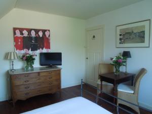 a bedroom with a tv on a dresser and a desk at Bed & Breakfast Frans Hals Haarlem in Haarlem