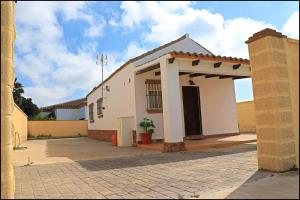 una pequeña casa blanca con una gran entrada en Bungalow complejo III, en Conil de la Frontera
