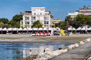 a beach with a building and some chairs and water at Hotel Petit Palais in Venice-Lido