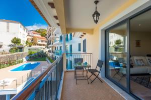 balcón con vistas a la piscina, mesa y sillas en Funchal SilverWood Apartment - by LovelyStay, en Funchal