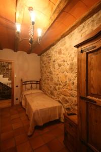 a bedroom with a bed and a stone wall at Casa Rural Cal Puyo in Paúls