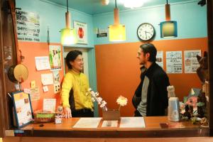 two men standing behind a counter in a store at Otohaya Guesthouse in Nagoya