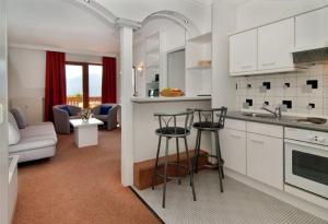 a kitchen with two bar stools and a living room at Appartementhaus im Himmelreich in Lam