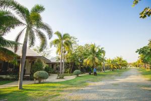 a person walking down a street with palm trees at Nisasiri Boutique Resort in Laem Sing