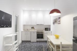 cocina blanca con armarios blancos y mesa en Groseko La Zurriola - IB. Apartments, en San Sebastián