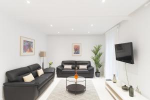 sala de estar con 2 sofás negros y TV en Groseko La Zurriola - IB. Apartments, en San Sebastián