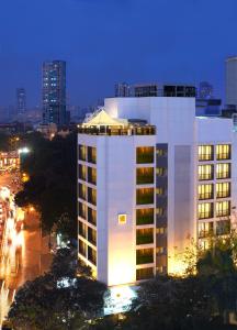 a tall white building with a city at night at The Shalimar Hotel, Kemps Corner in Mumbai
