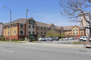a building on a street with cars parked in a parking lot at Extended Stay America Suites - Los Angeles - Torrance Blvd in Torrance