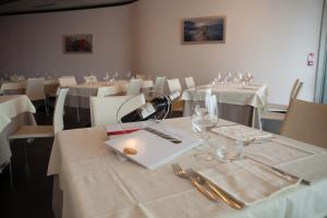 un comedor con mesas con manteles y vasos blancos en Klass Hotel, en Castelfidardo