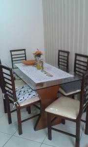 a dining room table with chairs and a table with flowers on it at Apto Arpoador Próximo Praia VV in Vila Velha