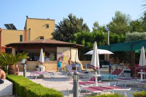 a group of lounge chairs and umbrellas and a bar at Happy Camp mobile homes in Camping Village La Masseria in Gallipoli