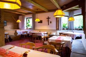 restauracja ze stołami i krzesłami oraz krzyżem na ścianie w obiekcie Pension Christoph w mieście Kramsach