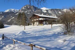 dom w śniegu z górami w tle w obiekcie Pension Christoph w mieście Kramsach
