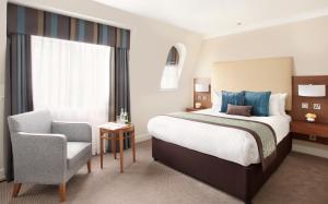 a hotel room with a bed and a chair at Thistle London Piccadilly in London
