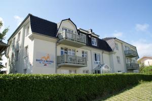 a large white building with balconies on the side of it at Am Weststrand Apartmenthaus Bellamare in Kühlungsborn