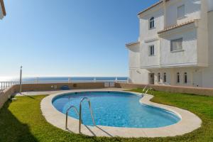 a swimming pool next to a building and the ocean at Casa Buenavista in Almuñécar