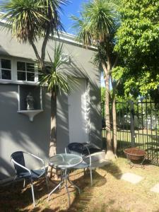 a patio with chairs and a table and palm trees at Villa Barry in Hout Bay