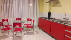 a kitchen with red cabinets and a table with red chairs at Apart Serma Hotel in Potosí