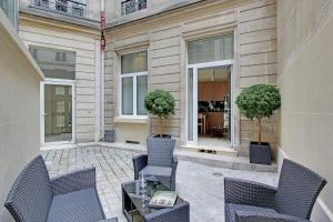 a patio with chairs and a table and windows at Milestay Opera Lafayette - Serviced Apartment in Paris