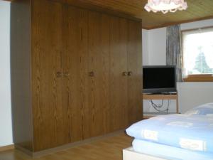 Säntisblick في Urnäsch: غرفة نوم مع باب خشبي كبير وتلفزيون
